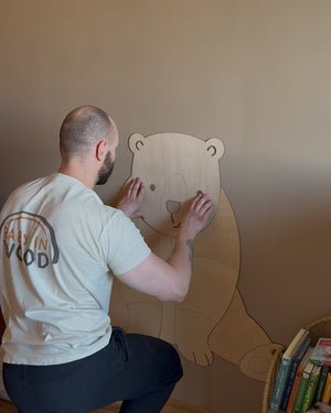Bastien pose la tête de l'ours en bois sur le mur de la chambre